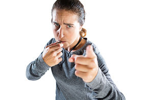 High angle portrait of female coach gesturing while whistling against white background