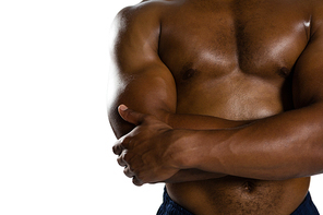 Mid section of shirtless male athlete with arms crossed standing against white background