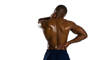 Rear view of shirtless sportsman suffering from pain while standing against white background