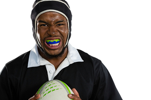 Portrait of male rugby player wearing mouthguard white holding rugby ball against white background