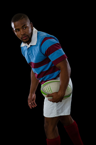 Side view of male athlete looking away while playing rugby against black background