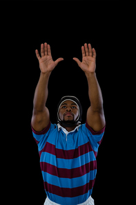 Sportsman with arms raised playing rugby against black background