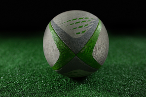 Close up rugby ball on field against black background