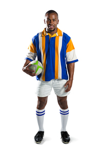 Portrait of happy rugby player holding ball while standing against white background
