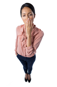 Portrait of female executive yawning on white background