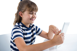 Cute girl using digital tablet at table against white background