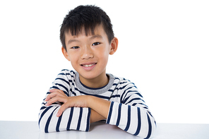 Portrait of smiling boy sitting against white background