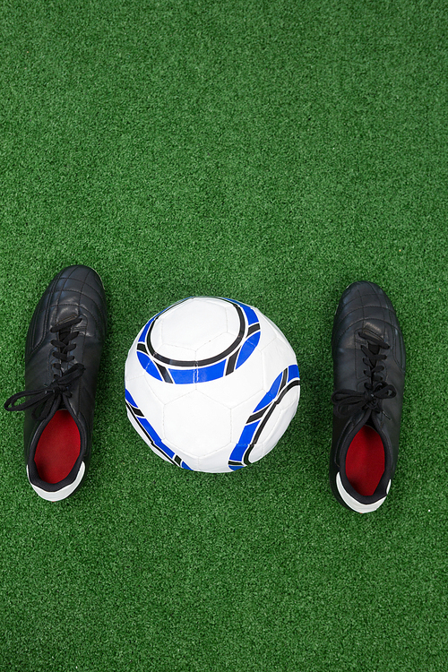 Overhead view of football and cleats on artificial grass