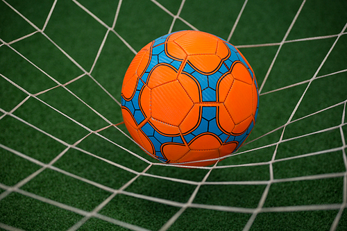 Close-up of football in goalpost against artificial grass