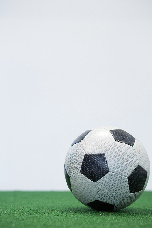 Football kept on artificial grass against white background