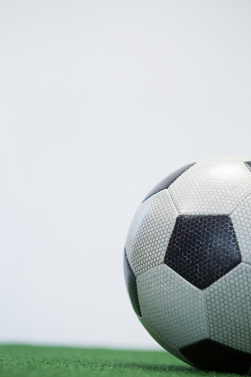 Close-up of football kept on artificial grass against white background