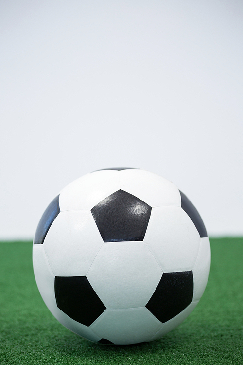 Close-up of football kept on artificial grass against white background