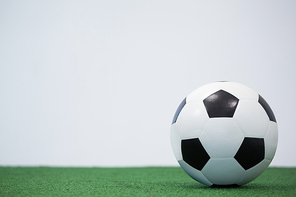 Football kept on artificial grass against white background