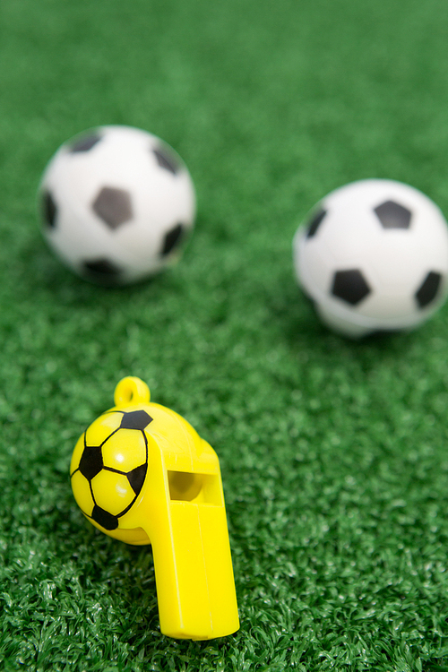 Close-up of whistle and footballs on artificial grass