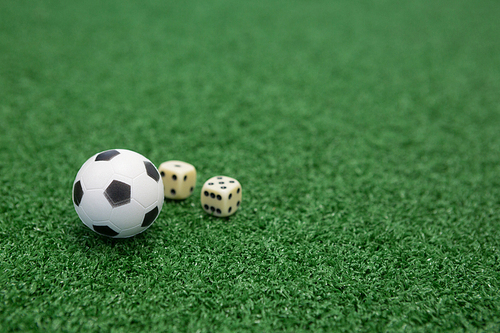 Close-up of football and dices on artificial grass