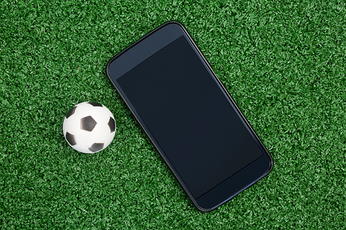 Close-up of football and mobile phone on artificial grass