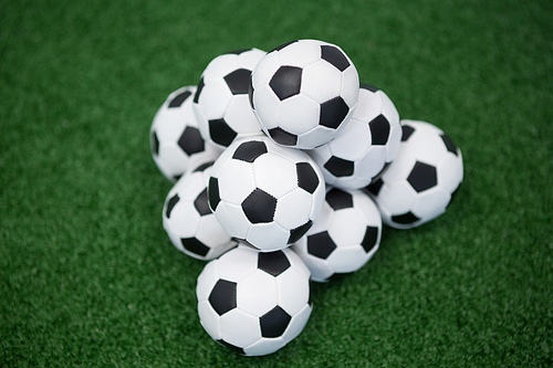 Stack of piled up football soccer balls on artificial grass