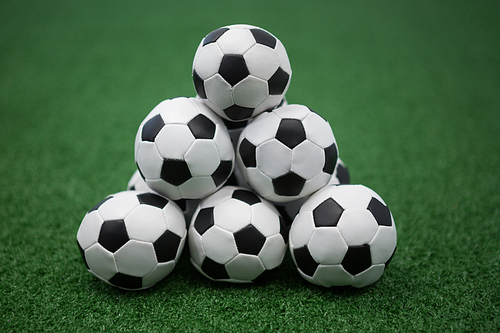 Stack of piled up football soccer balls on artificial grass