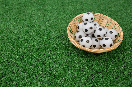 Footballs in wicker basket on artificial grass