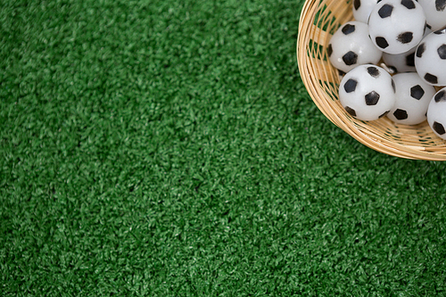 Overhead view of footballs in wicker basket on artificial grass