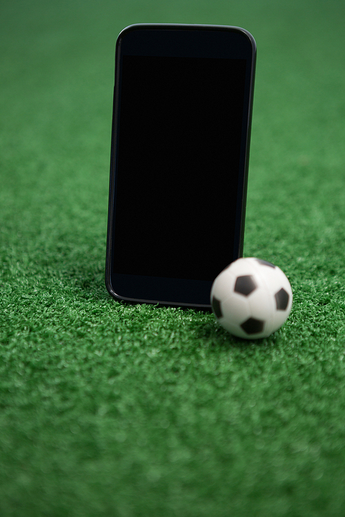 Close-up of football and mobile phone on artificial grass