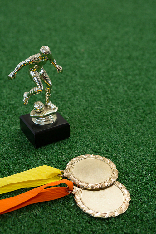 Close-up of trophy and medals on artificial grass