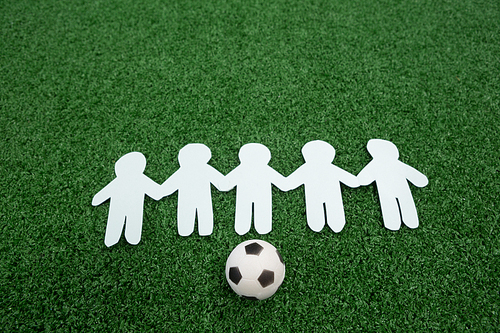 Close-up of paper cut outs and footballs arranged on artificial grass