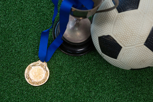 Close-up of football, trophy and medal on artificial grass