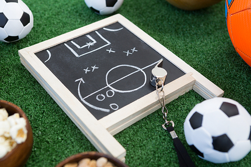 Close-up of strategy board, whistle and football on artificial grass