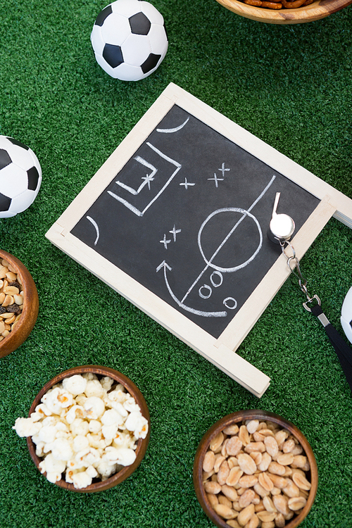 Overhead view of strategy board, whistle and football on artificial grass