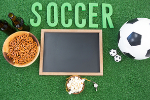 Close-up of chalk board, snacks and football on artificial grass