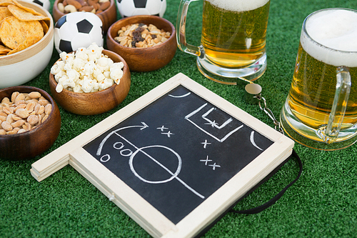 Close-up of strategy board, football and snacks on artificial grass