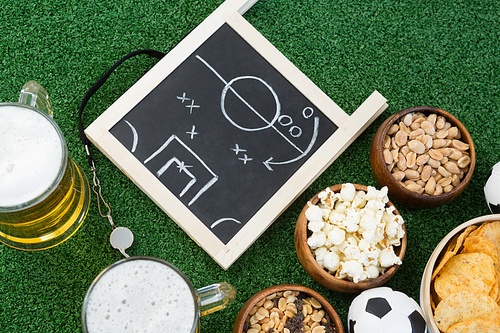 Close-up of strategy board, football and snacks on artificial grass