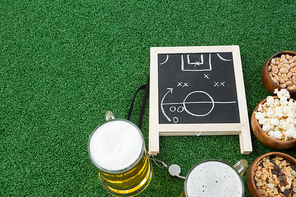 Overhead view of strategy board, football and snacks on artificial grass