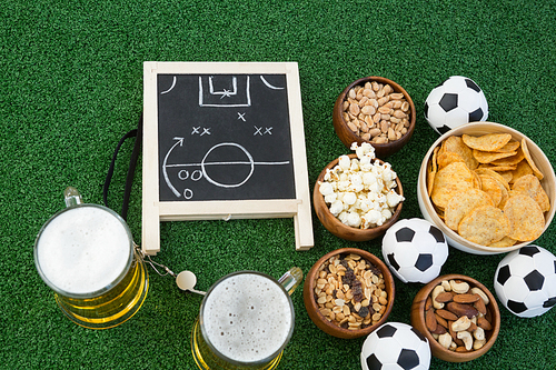 Overhead view of strategy board, football and snacks on artificial grass