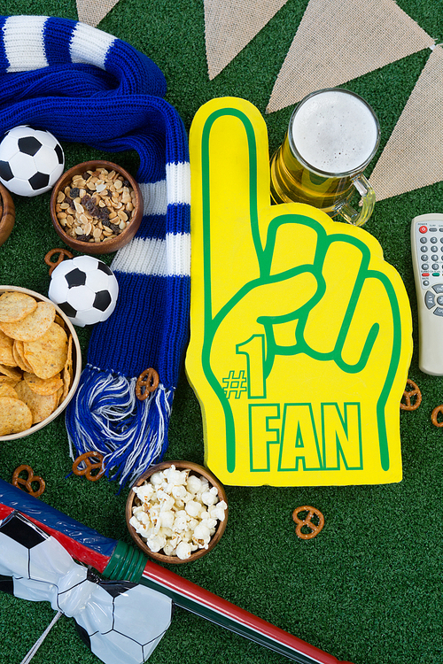 Close-up of foam hand, snacks and footballs on artificial grass