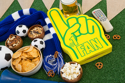 Close-up of foam hand, snacks and footballs on artificial grass