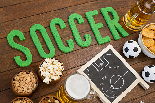 Overhead of strategy board, snacks and football on wooden table