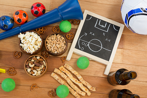 Overhead of strategy board, snacks, drink and football on wooden table