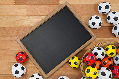 Overhead of colorful footballs and slate on wooden table