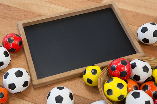 Close-up of colorful footballs and slate on wooden table