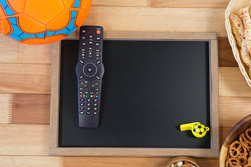 Overhead of snacks, football, whistle and slate on wooden table