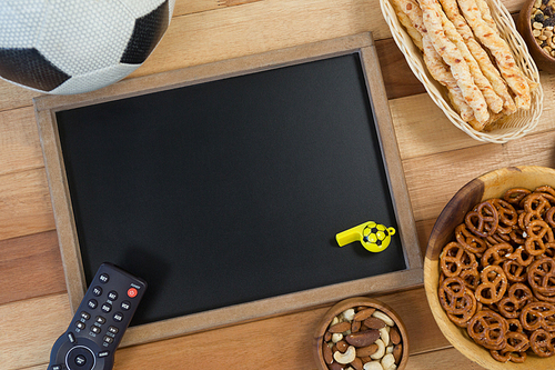 Overhead of snacks, football, whistle and slate on wooden table