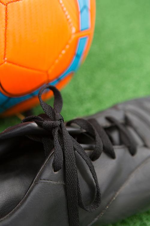 Close-up of football and cleats on artificial grass