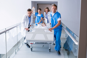 Doctors pushing emergency stretcher bed in corridor at hospital