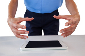 Mid section of businesswoman gesturing over tablet computer against white background