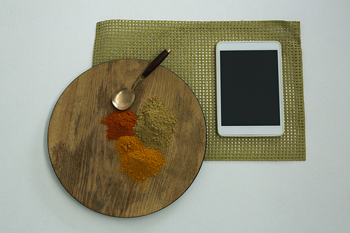 Overhead of various type of spices on wooden board with digital tablet