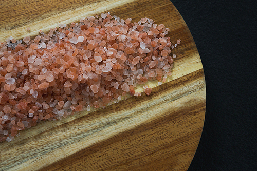Close-up of himalayan salt in wooden board on black background