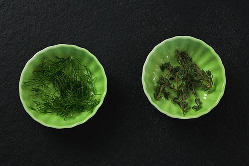 Dill and rosemary in bowl on black background