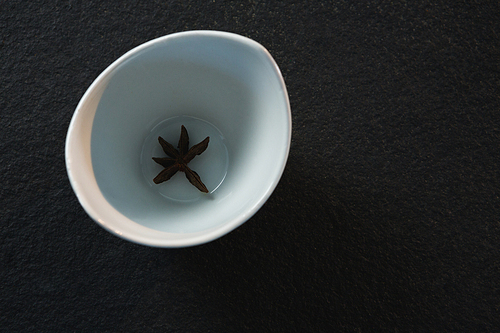 Close-up of star anise on a bowl on black background